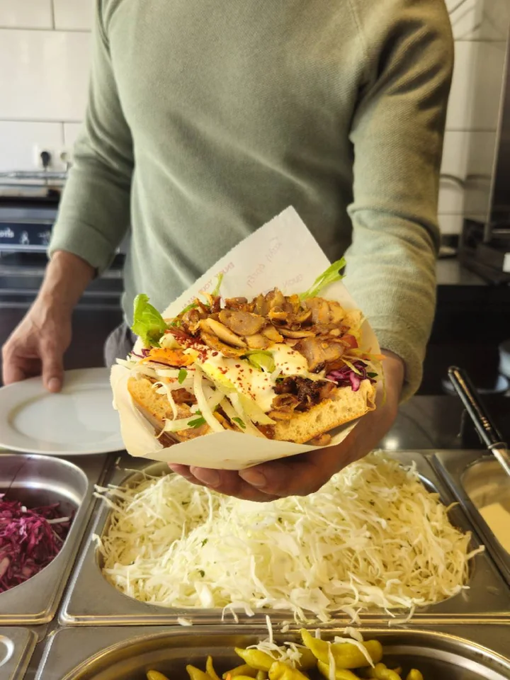 Ein Mitarbeiter reicht einen gefüllten Döner über die Theke